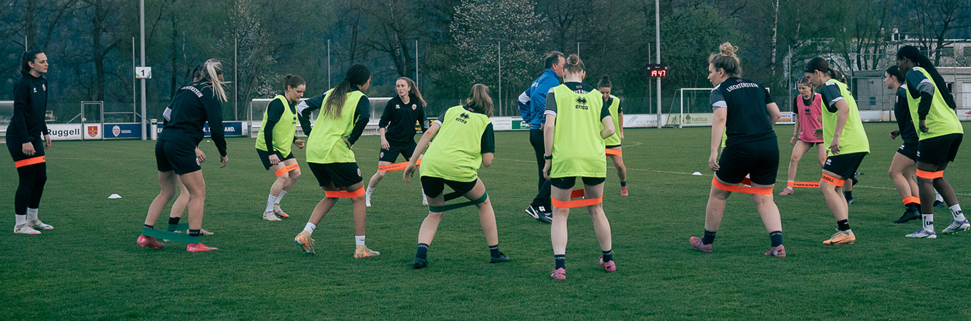 Das Foto zeigt das Team bei Aufwärmübungen im Kreis.